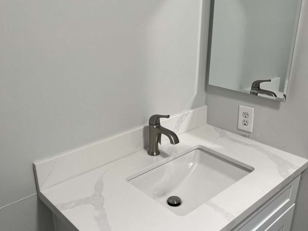 White bathroom vanity with new faucet and marble-look top