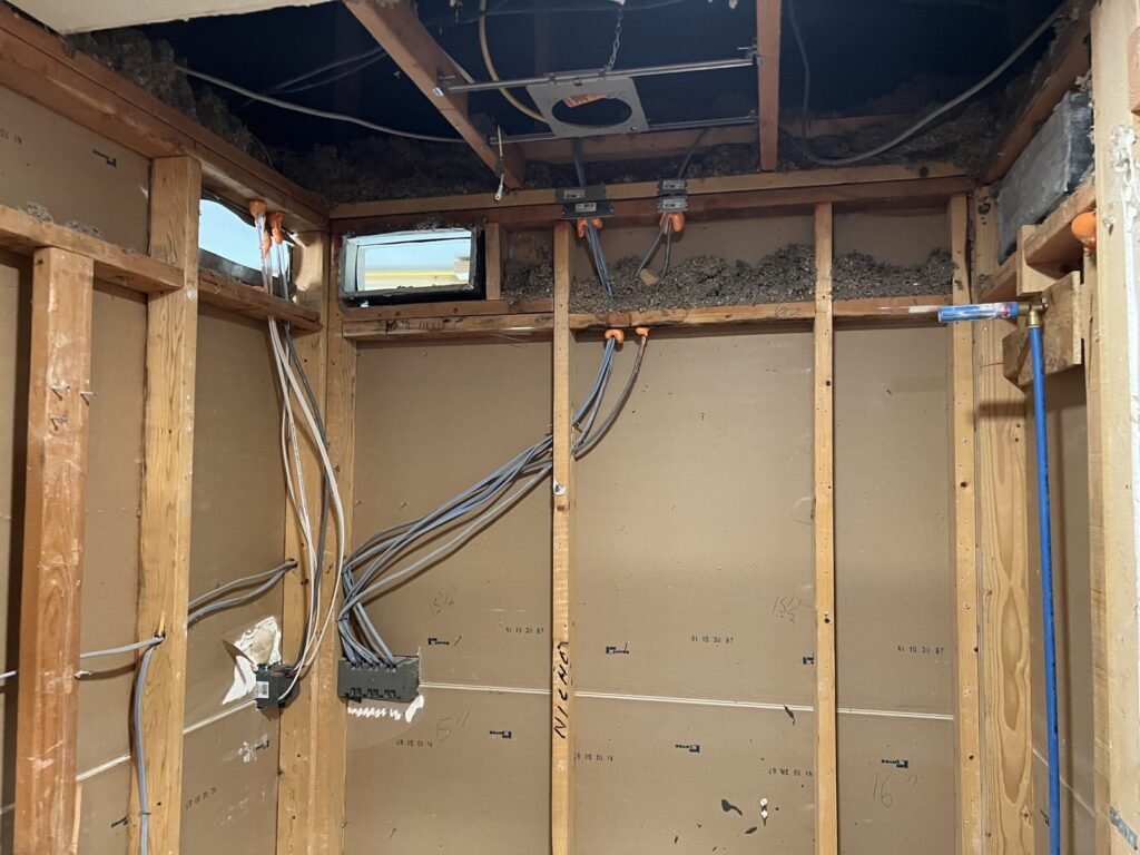 Bathroom stripped back to studs with wiring and plumbing exposed