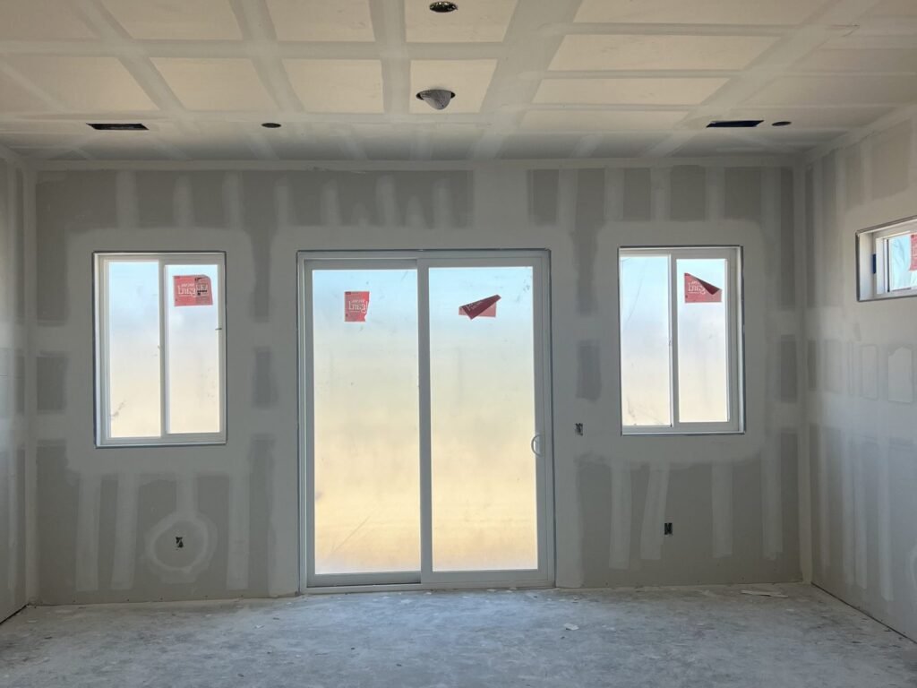 Drywall panels installed across a living area wall and ceiling