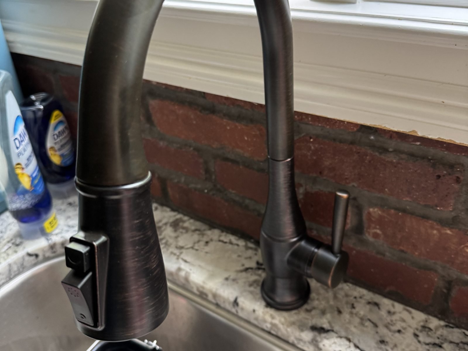 New pull-down kitchen faucet at a sink with granite countertop
