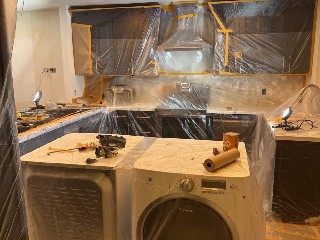 Kitchen appliances and cabinets masked in plastic sheeting before work