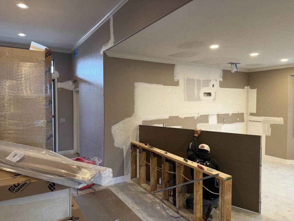 Drywall patched and skim-coated around a kitchen pass-through under construction