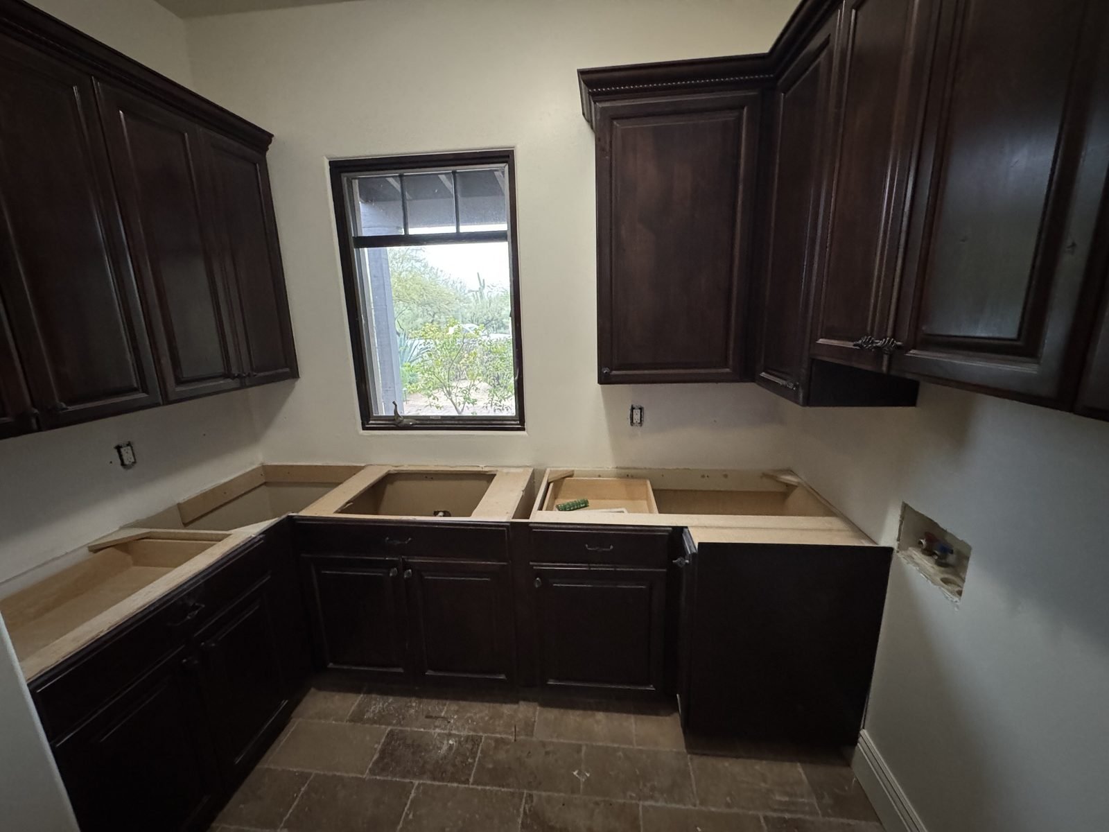 Laundry room with dark-stained cabinets around the window before painting