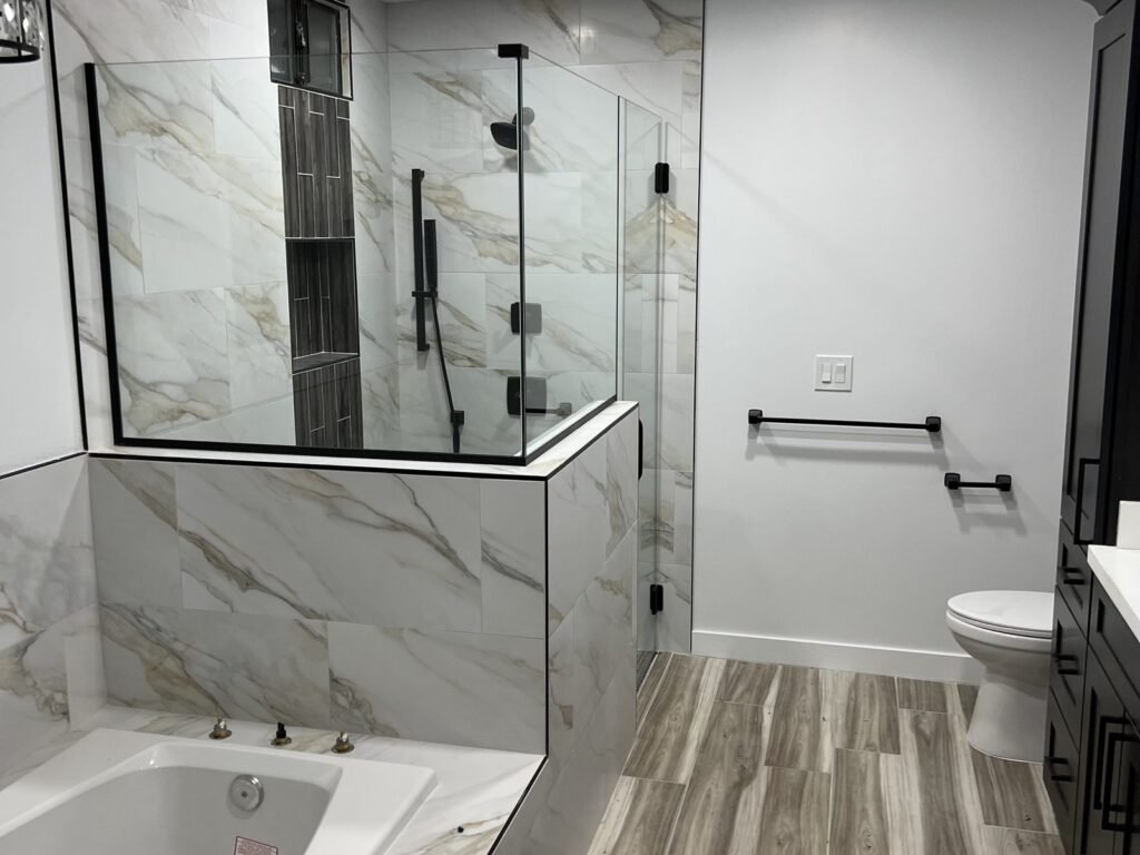 Walk-in shower tiled in large marble-look panels with glass screen