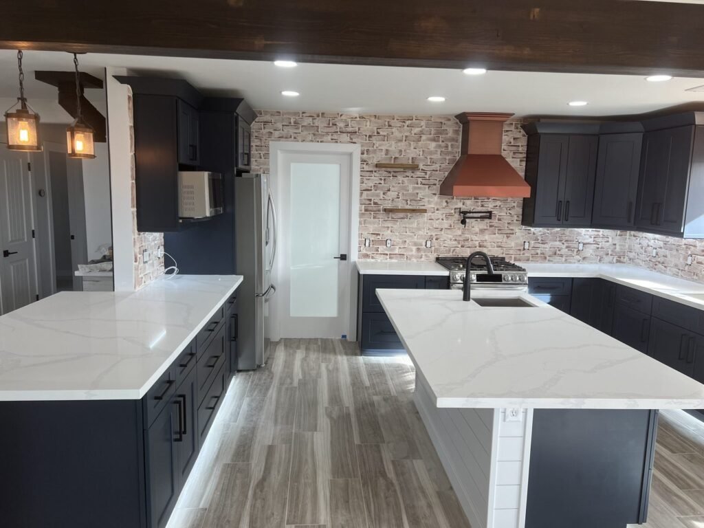 Kitchen with dark cabinetry, copper range hood and marble-look island