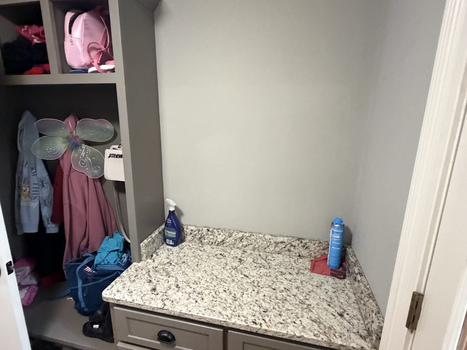 Mudroom counter and cubbies with the wall above bare, before the new upper cabinet was installed