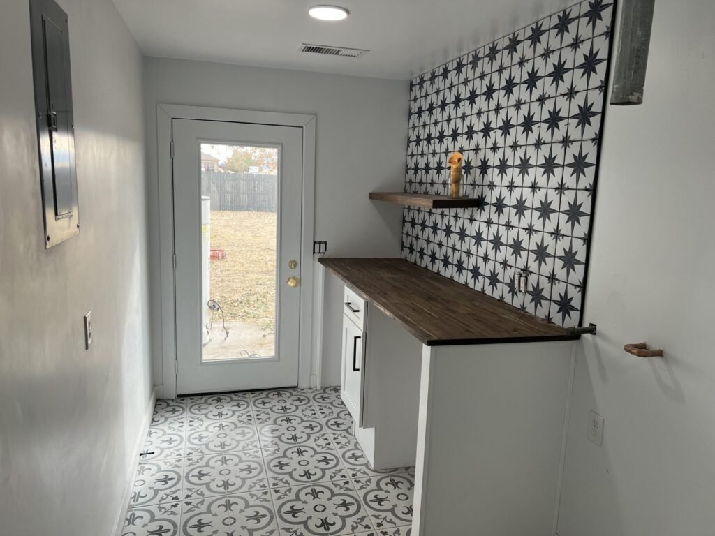 Narrow room with patterned accent wall and patterned tile floor