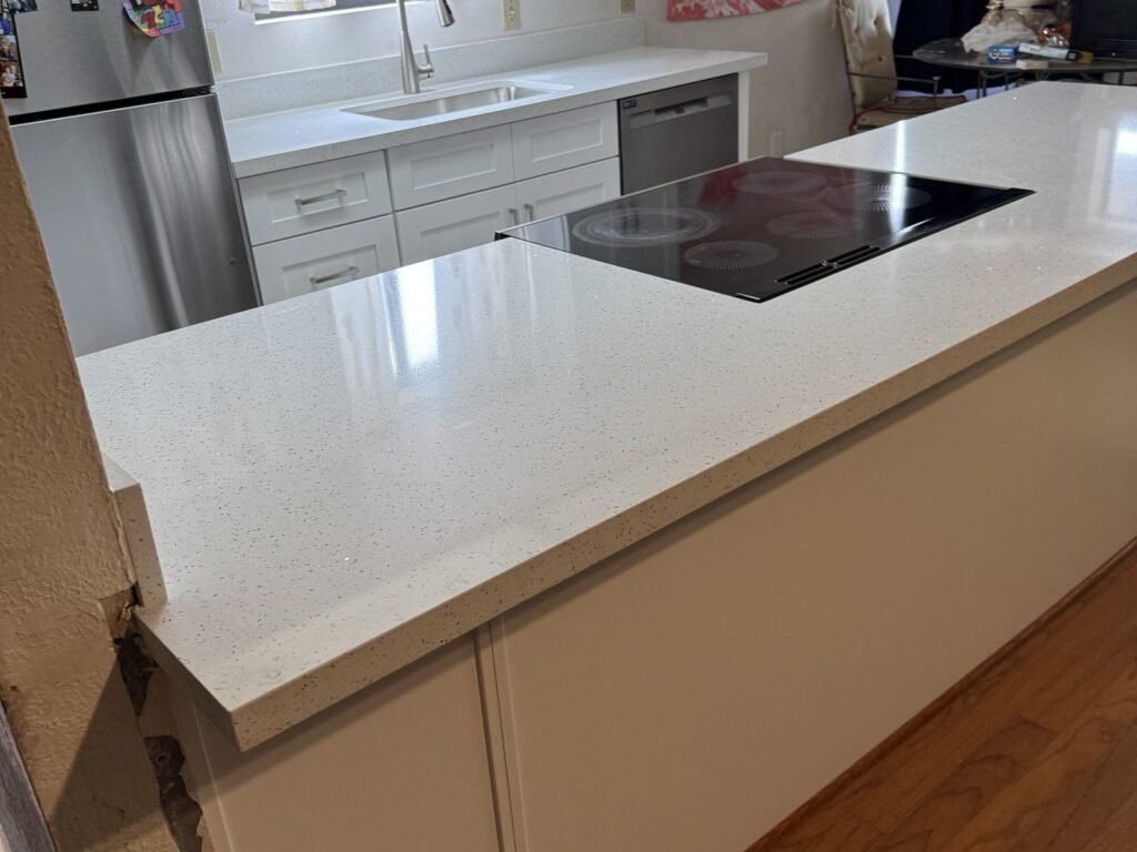Kitchen peninsula with white quartz countertop and induction cooktop